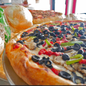 Close-up of a pizza topped with olives, green peppers, and cheese.