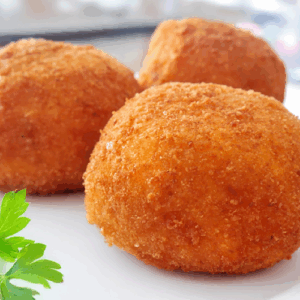 Golden-brown breaded croquettes on a white plate with parsley garnish.