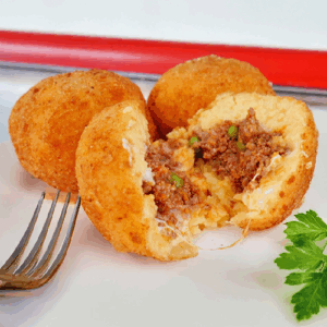 Two golden brown stuffed croquettes with a fork and parsley on the side.