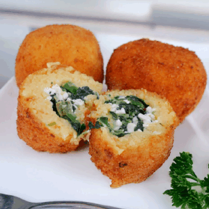 Golden fried spinach and cheese croquettes on a white plate.